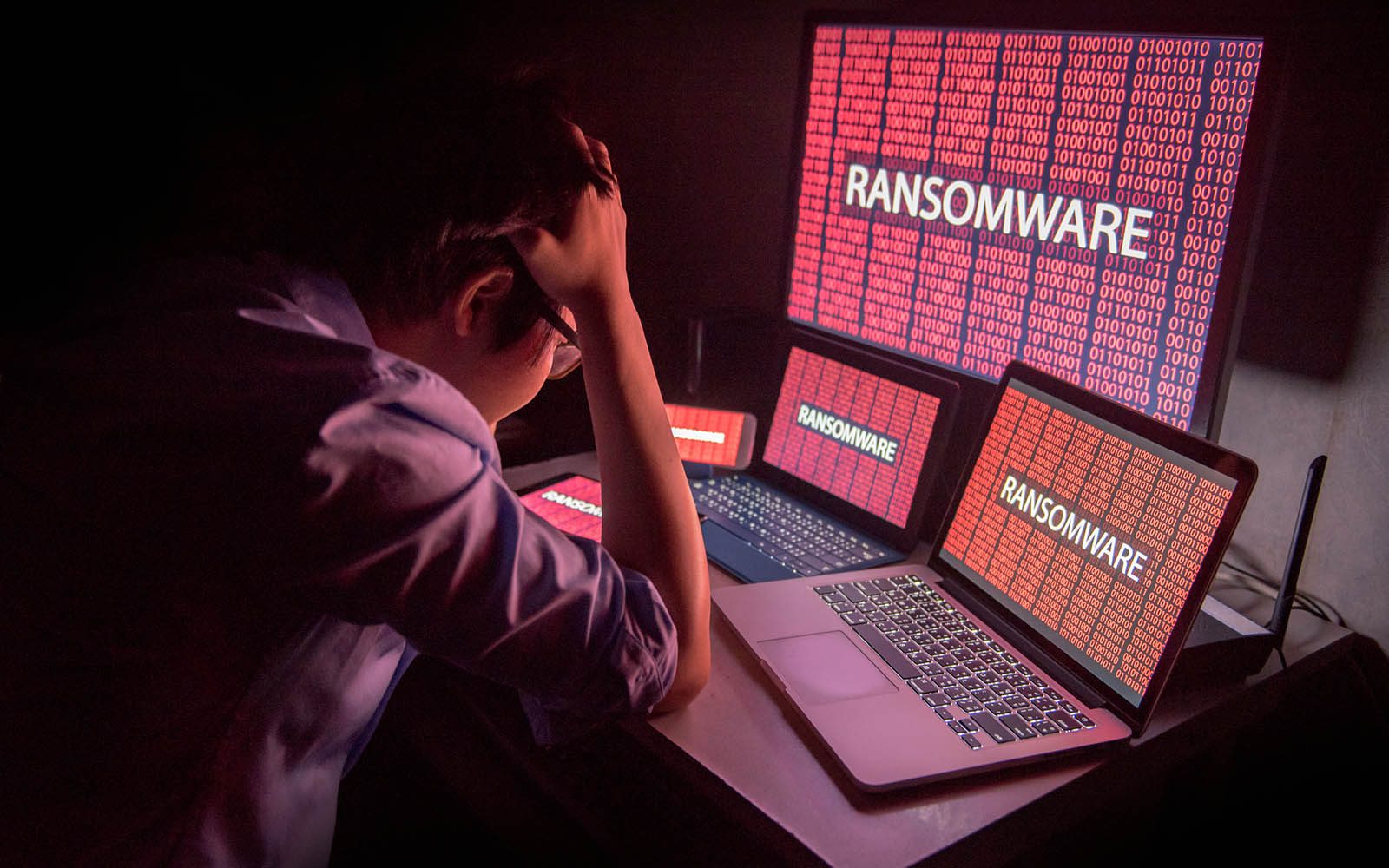 Young Asian male frustrated by ransomware cyber attack Young Asian male frustrated, confused and headache by ransomware attack on desktop screen, notebook and smartphone, cyber attack and internet security concepts